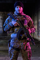 Obraz premium Armed Soldier in Camouflage Tactical Gear Holding Rifle in Urban Night Setting