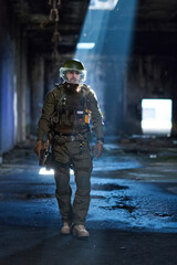 Obraz premium Armed Tactical Soldier With Protective Visor Walking Through Dimly Lit Abandoned Building