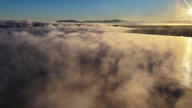 Aerial video of Lake Keepit Dam blanketed by morning fog in NSW, Australia. Low cloud drifts across the reservoir and surrounding landscape