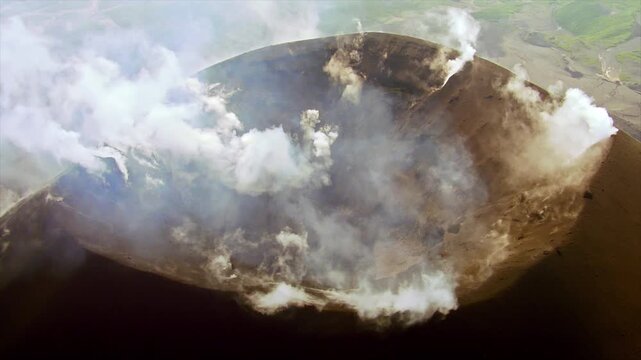 Stunning aerial shot revealing an active volcano's crater emitting smoke and gas from fumaroles