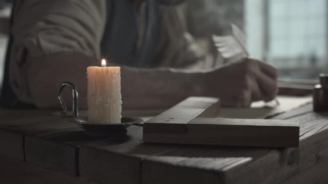 Craftsman sketching flying machine wings with a feather pen next to a wooden square ruler and a lit candle on a rustic desk inside an artist studio, tracking shot