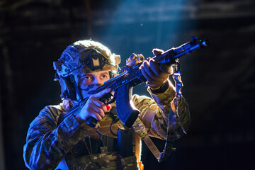 Fototapeta premium Soldier in Tactical Gear Aiming Rifle Under Dramatic Lighting During Night Training Exercise