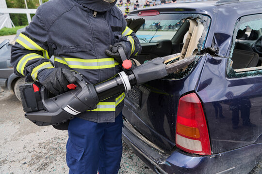 Firefighter Using Hydraulic Rescue Cutter To Remove Car Rear Panel During Emergency Vehicle Extrication Training