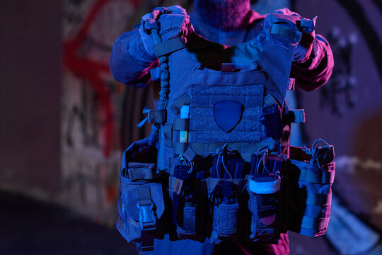 Tactical Plate Carrier Vest With Pouches and Gear Held by Operator in Urban Night Lighting