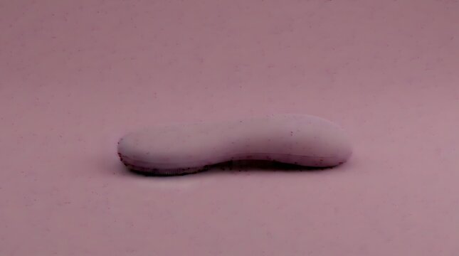Single smooth oblong pink bar of soap resting on a matching solid pastel pink surface with soft studio lighting effects
