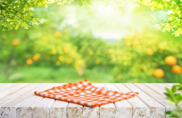 Red fabric cloth on wood table top with blur of orange garden farm background © hakinmhan