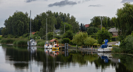 Fototapeta premium Sailboats and boats moored at a small marina on the Szkarpawa River.