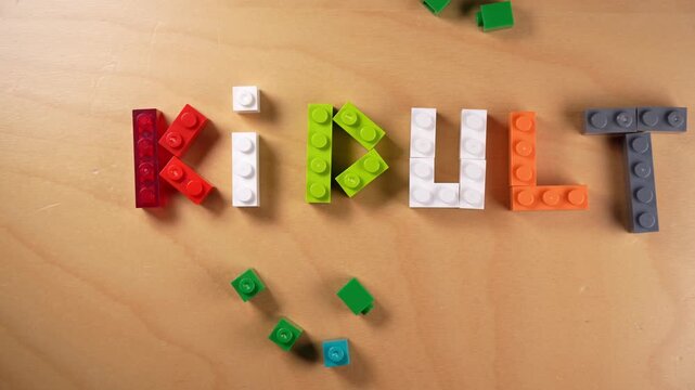 Animated stop motion construction of the word kidult, a portmanteau for adults who enjoy youth culture and entertainment, built with multicolored toy blocks on a bright wooden background