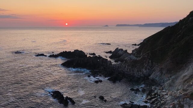 flying towards the sunrise on the rocky Atlantic coast in Cudillero, Asturias, travel in northern Spain, Cudillero lighthouse drone shot at sunrise, travel and adventure concept