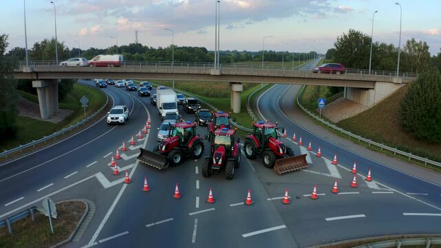 farmers blocking highway with tractors and cones, organized road protest causing traffic disruption, aerial view near overpass, demonstration against policies, transport interruption and civil unrest