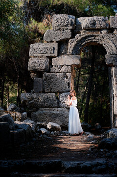 Young beautiful woman wering white dress at antique ruin