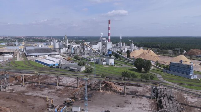 Aerial view of modern pulp and paper mill plant with industrial machinery and wood chips for manufacturing and supply chain