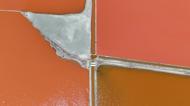 Aerial drone view of pink salt evaporation ponds. Geometric pools and white salt mounds create a unique landscape. Burgas, Bulgaria. 