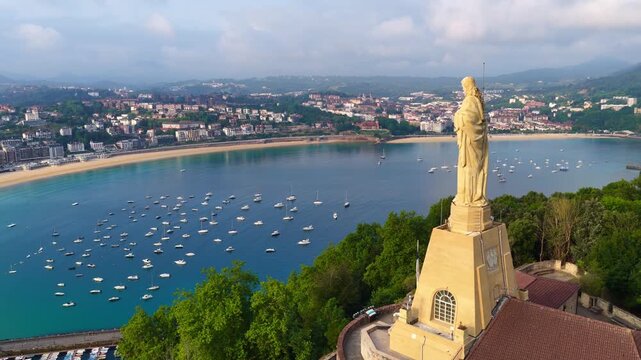 Morning aerial view of San Sebasti&aacute;n city in Basque Country, northern Spain. Orbiting drone shot of Jesus Christ statue in San Sebasti&aacute;n old town, vacation in Basque Country