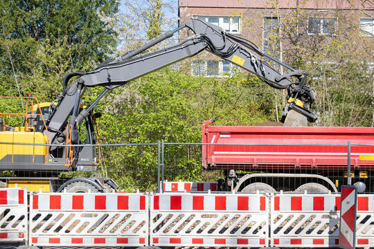 Bagger bel&auml;dt Kipplaster mit Erdreich auf einer Baustelle