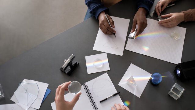 Hands exploring light and prisms in physics class