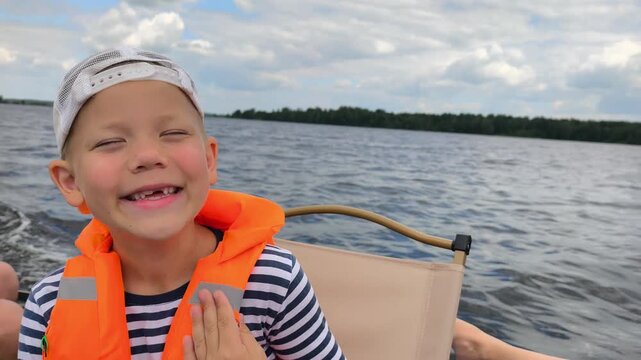 A cheerful child in a bright orange life jacket enjoys a safe boat ride on calm waters, showcasing the importance of water safety gear while capturing the joy and freedom of a sunny day out on lake