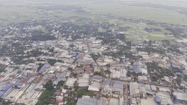 Drone shot with a steady leftward movement over an industrial and residential area in Khajanagar, Kushtia, featuring factories, infrastructure, buildings, and rural surroundings.