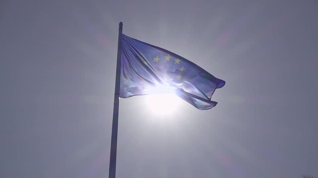 European Union flag fluttering on a flagpole against a shining sun, symbolizing unity, prosperity, and the welfare state with a strong sense of community and successful economic integration