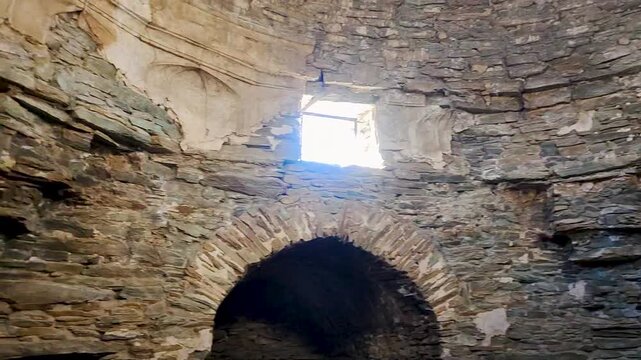 The interior stone walls inside Tash Rabat caravanserai in Kyrgyzstan. The video captures a skylight windows, arched doorways and medieval stone masonry.