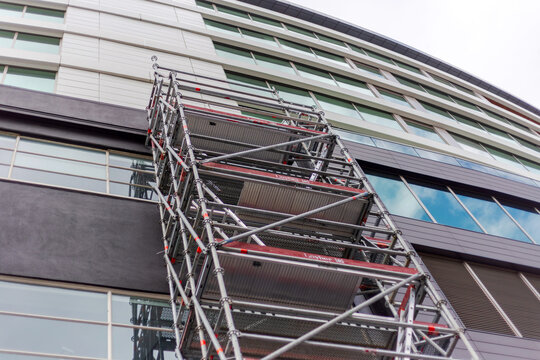 A tall metal scaffolding tower stands against a modern multi‑story building in Wellington, New Zealand