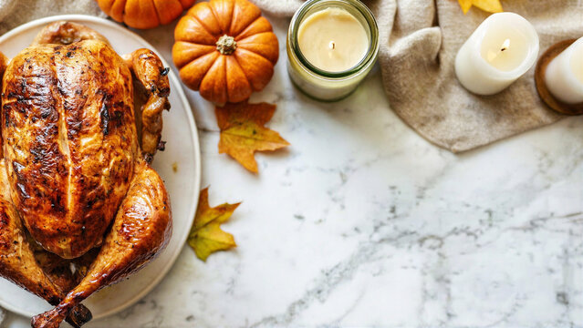 Minimal Thanksgiving table setting with pumpkins and candles in a bright kitchen. Cozy autumn dining interior concept.