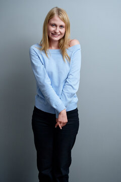 Smiling Woman in Blue Sweater Against Neutral Grey Background