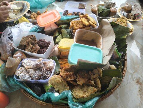Various traditional Indonesian cakes and snacks like lemper, risol, klepon in a bamboo woven tray.