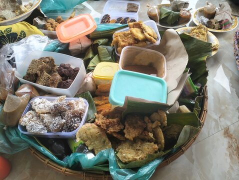 Various traditional Indonesian cakes and snacks like lemper, risol, klepon in a bamboo woven tray.