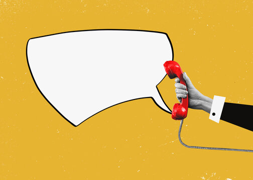 A hand holding a red landline with speech bubble as copy space.