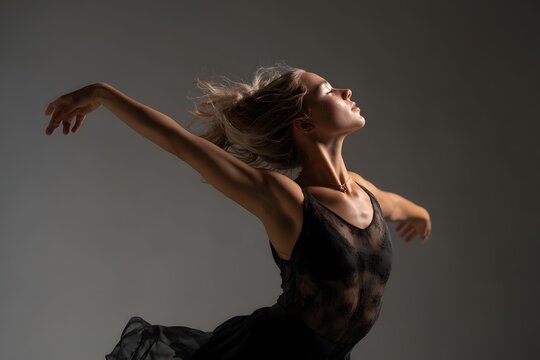 Woman Dancing Gracefully in Dark Studio with Dramatic Lighting and Emotional Expression