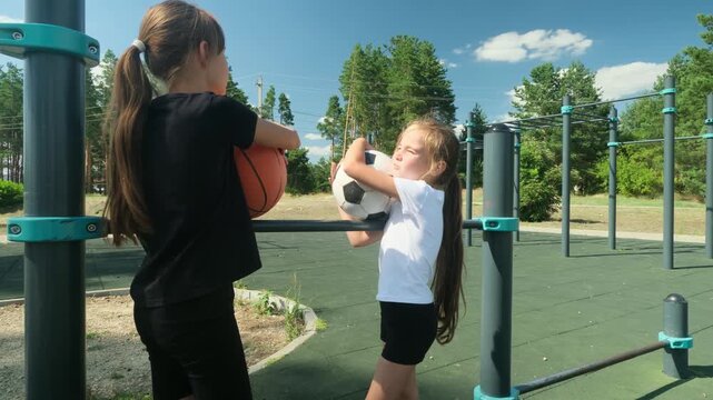 Two girls face each other outdoors, holding basketball and soccer ball. Friendship links different interests, friendship builds trust, and friendship turns sport choice into shared childhood.