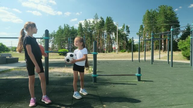 Two girls prepare for basketball and soccer beside workout equipment. Multisport activity builds versatility, multisport activity expands skills, and multisport activity keeps childhood active.