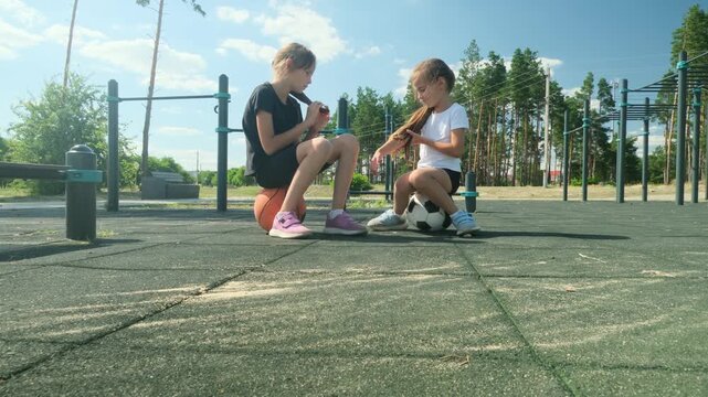 Two girls prepare for basketball and soccer beside workout equipment. Multisport activity builds versatility, multisport activity expands skills, and multisport activity keeps childhood active.