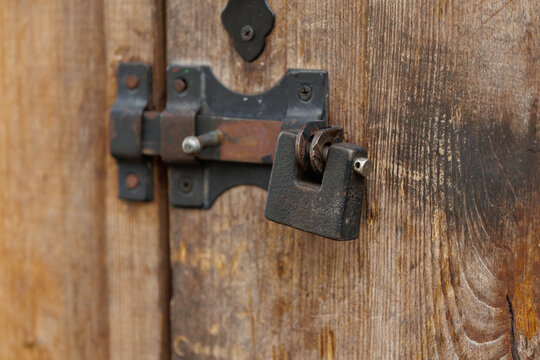 Vintage metal padlock and latch on an old weathered wooden door