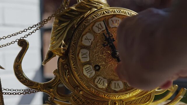 Person winding up an antique golden wall clock