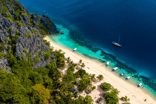Aerial view of Black island in the Philippines with beautiful sand beach, stranded shipwreck and moared boats. 