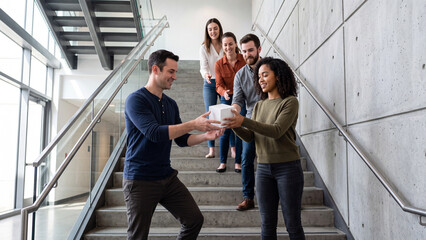 Obraz premium Diverse team collaborating and passing a white cube on a modern office staircase.