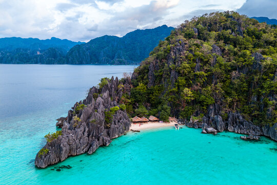 Aerial view of small private sand beach, azure blue water and tropical island with limestone rocks in Coron, the Philippines
