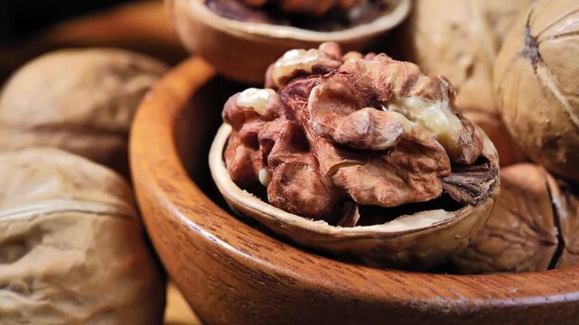Fresh organic walnuts in a rustic wooden bowl on a wooden table. Healthy natural nuts rich in nutrients, suitable for healthy eating, snacks, and food backgrounds.