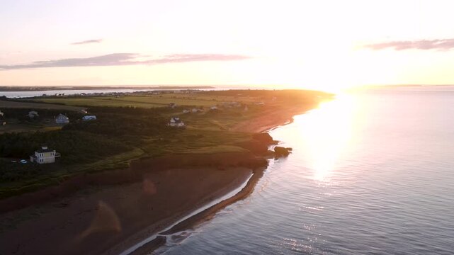 Sunrise over Gulf of St Lawrence and red coast of Prince Edward Island, aerial shot. Thunder Cove coastline in golden sunlight