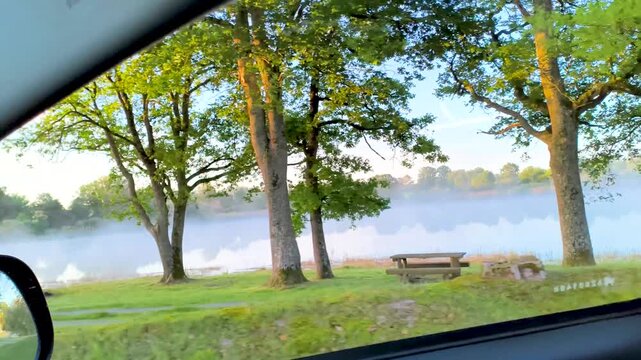 Morning mist over lake viewed from car window