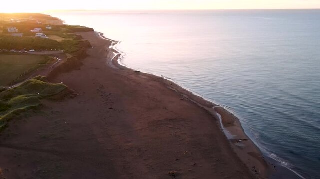 Aerial flight along red sandy beach and dunes, Prince Edward Island coastline, Canada