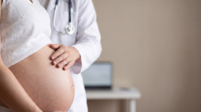 Doctor examining a pregnant woman's abdomen during a prenatal healthcare visit