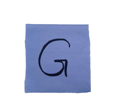 Handwritten black letter g on a light blue paper square against a solid , simple uppercase g