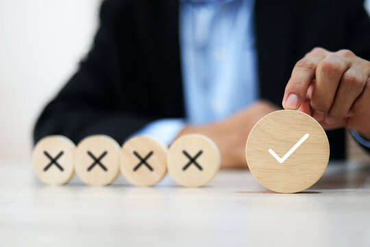 Hand choose check mark with cross symbol on wooden toy stack for true or false changing mindset or way of adapting to change leader and transform quiz answer and poll concept.