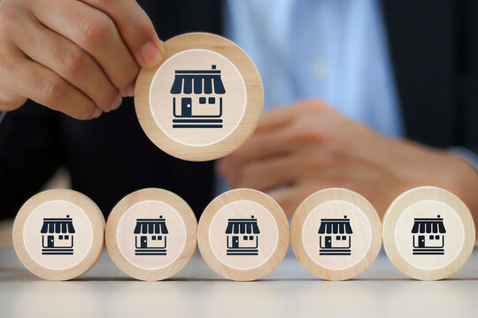 Businessman's hand chooses wooden toy stack with franchise icon for goal to growth is investment planning financial and branch expansion and management bank loans for marketing franchising.