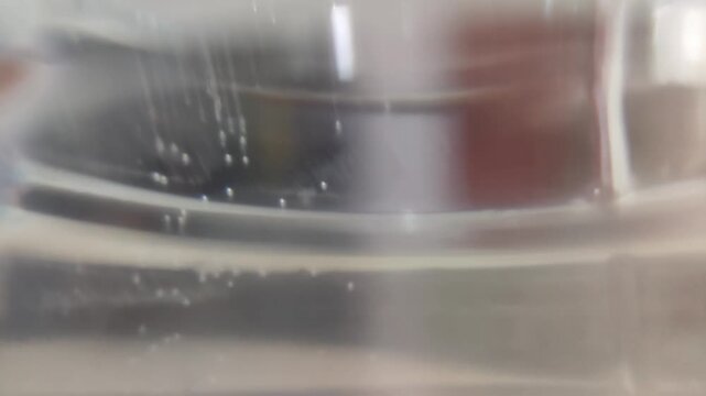 Close-up shot of small white spheres floating inside a clear glass container filled with water