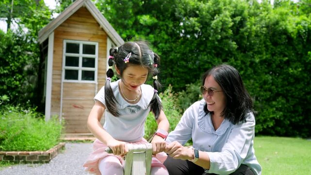 Happy Asian Child Playing Outdoors with Caring Female Guardian in Green Garden, Family Bonding and Childhood Lifestyle Concept Under Natural Sunlight