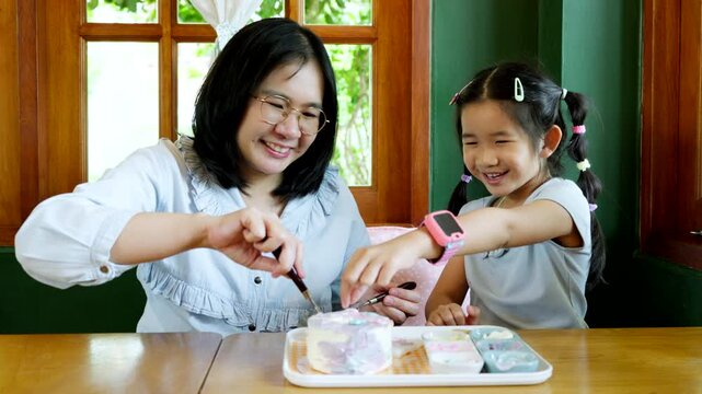 Asian Child Decorating Cake with Caring Parent at Home, Family Bonding and Quality Time During Creative Indoor Activity